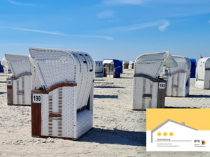 Das Bild zeigt einen sonnigen Nordseestrand mit weißen Strandkörben und die Tafel der 3-Sterne-DTV-Klassifizierung.